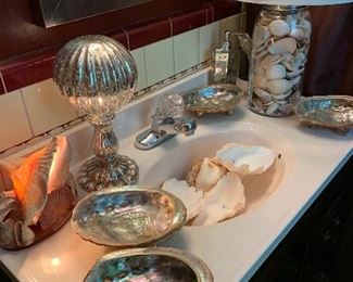 The bathroom vanity filled with seashells and a shell lamp. 