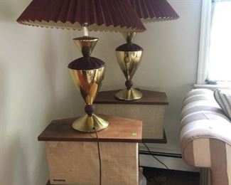 pair of brass lamps sitting on a pair of Bose speakers