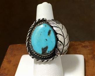 #9...Really beautiful size 7 1/4 Native American made silver ring with slightly teardrop-shaped turquoise cabochon in smooth bezel rimmed with silver twisted wire. Finished with a large curved silver feather on the right and carved silver outer framing on the left. Split shank band. $280