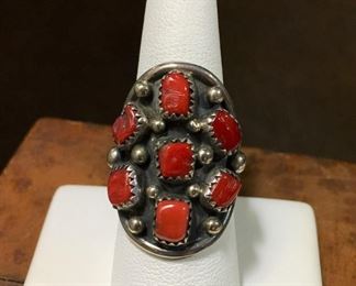 #50...Signed size 7 1/2 Native American made sterling silver saddle style cluster ring. Features seven coral cabochons set in sawtooth bezels with twelve silver rain drops artfully placed all around. Signed D, stamped Sterling. $180