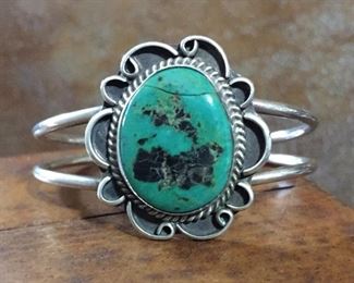 #34...Signed Native American old pawn sterling silver and turquoise cuff bracelet. Center medallion is 1 1/4" x 1 3/8". Total circ. 6 1/4" (5 1/8" inner circ. with 1 1/8" gap). Signed MT. Very slightly flexible. Note - turquoise is cracked - priced accordingly. $125