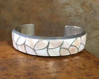 #35...Signed Native American made sterling silver cuff bracelet with blush-pink mother of pearl inlays all around. Bracelet width is 5/8". Total circ. 6 3/8" (5 1/8" inner circ. with 1 1/4" gap). Not flexible. Signed STM. $260