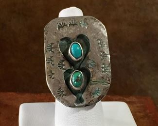 #48...Unique design! Size 5 1 /2 Native American made silver ring with two small oval turquoise cabochons (one has a large pyrite fleck) set inside heart-shaped cut-outs. Stamped silver background. $200.