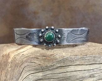 #58...Harvey era Native American sterling silver cuff bracelet with small round green turquoise cabochon and tribal stampings. Tapered width of 1/2" (center front) to 1/4" in back. Total circ. 6 1/2" (5 3/8" inner circ. with 1 1/8" gap). Signed IH, stamped SILVER. Flexible. $280