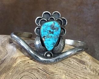 #63...Signed Native American made sterling silver and turquoise cuff bracelet. The center medallion features a gorgeous teardrop-shaped turquoise cabochon sprinkled with pyrite flecks and framed around the bottom with a silver teardrop and two silver feathers. Center medallion is 7/8" x 1 1/4". Total circ. 6 1/2" (5 1/4" inner circ. with 1 1/4" gap). Signed DS 1911 J.F. $290