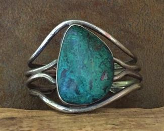 #64...Native American made sterling silver and eilat stone cuff bracelet. Features a large, beautiful deep teal/green-colored eilat stone. Total 6 3/8" circ. (5 1/2" inner circ. With 7/8" gap). Size of framed cabochon is 1 1/16" x 1 1/2". Not flexible. $350