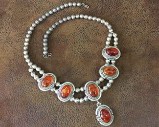 #66...Gorgeous RARE signed 21" long sterling silver and amber necklace with 102 7mm sterling bench beads. Made by Navajo artisan silversmith Esther Spencer. Featuring five baltic amber stations and a drop pendant, all set in sterling silver. Stations and pendant are 7/8" x 1 1/16" h; pendant hangs down 1 1/4". Signed E. Spencer, stamped Sterling. $900