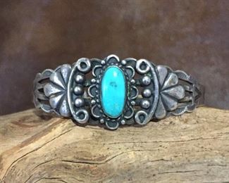 #86...Harvey era sterling silver cuff bracelet with an oval turquoise cabochon, silver decorations and stampings (including snakes, suns and teepees). Width tapers from 7/8" (front center) to 1/4" in back. Total circ. 6 1/8" (5" inner circ. with 1 1/8" gap). Slightly flexible. $300