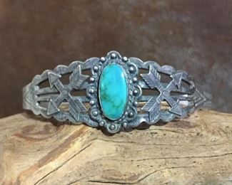 #82...Harvey era Native American sterling silver cuff bracelet with oval turquoise cabochon and crossed arrows w/tribal stampings on each side. Tapered width of 7/8" (center front) to 1/4" in back. Total circ. 6 5/8" (5 3/8" inner circ. with 1 1/4" gap). Stamped STERLING. Slightly flexible. $290