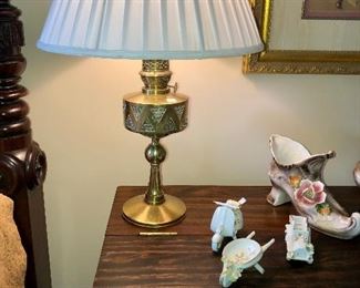 TURKISH ANTIQUE BRASS OIL LAMP CONVERTED TO ELECTRIC WITH FABRIC SHADE, SHOWN WITH CAPODIMONTE PIECES.