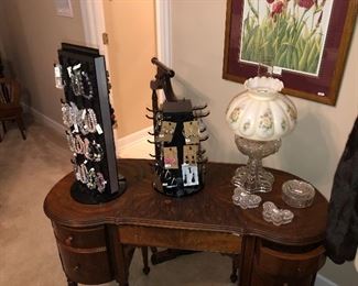 costume jewelry on a kidney shaped mahogany desk or make up table