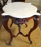 401 - Walnut Victorian Turtle Top Table in the rococo style with ladies heads and carved stretcher with white marble, 29 in. T, 43 in. W, 30 in. D, ca. 1850.