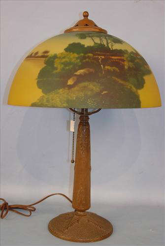 253 - Metal Base Lamp with reverse painted glass shade, lake and bridge scene, 22in. T, 15in. Dia. Ca. 1920.