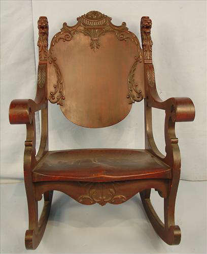 397 - Heavily Carved Mahogany Rocking chair with lions heads on either side of back, made by Horner, ca. 1890, 41in. T, 28in. W, 22in. D.