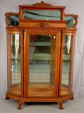 301 - Large oak curved glass china cabinet with lion heads in crown, top mirror panel, glass shelves, claw feet, exceptional quality, 82in. T, 57in. W, 17in. D, ca. 1900.