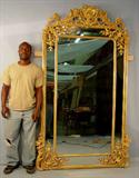 143- Gold leaf Victorian hanging mirror with ornate crown, extra applied fret work over glass. 53in. W, 90in. T.