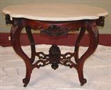 113 - Walnut Victorian turtle  top table with white marble and carved flower basket in original finish, 29in. T, 36in. W, 29in. D.
