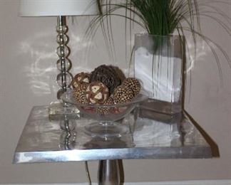Polished Aluminum Pedestal Table (24” x 24” x 23.H). Also shown: Herminie Stacked Ball Acrylic Table Lamp (1 of 2 shown), Block Glass Vase with Faux Wild Grass and Pedestal Glass 12”D Bowl with Decorative Natural & Ceramic Balls