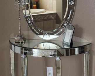 Venetian Style Etched Mirrored Glass Demilune Table (29.5”H x 40”W x 17”D) with Oval Mirror (26” x 56”) shown with a Tall 36” Metal Candle Stick Lamp with Crystal Prisms and Square Cloth Shade and a Noble Elegance Venetian Collection 5 x 7 Frame