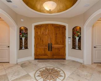 Entry View Facing Front Door Showing Tall White Blown Art Glass Trumpet Vases with Floral Arrangements.  (2 of 4 shown) 