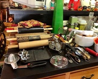 A stack of rolling pins, tall bright green glass vase,  pyrex bowls, paperweights, to the left bentwood rocker