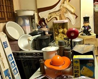 Abstract painting, enamel pans and pots, metal coke tags, orange glass hat, old thermos bottles, gas stove.