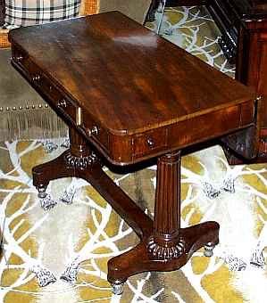 A GEORGE IV MAHOGANY INVALID'S TABLE
CIRCA 1830
The rounded rectangular top with flap to the back over three frieze drawers, on turned tapering gadrooned trestle supports joined by a stretcher, the tapering brass feet with gadrooned collars, on casters
29 in. high; 36 in. wide; 20 1/2 in. deep (closed)      Appraised Value: $2500.00