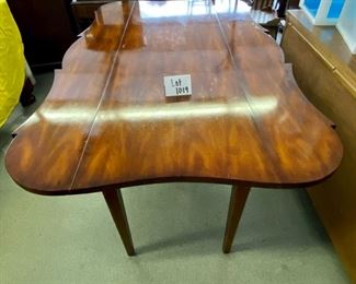 Lot 1019  Buy it Now $750.00	Talk about a multifaceted piece! Unbranded. Interesting shaped!  Can be a sofa table, game table, side table. Has two pull out trays and drop leaf sides. Does have some chips on the top, but they seem to diappear with a little old english. Hardwod! 42" w (w/leaves up), 23.5"w (w/leaves dropped)  x 66"L x 30.5" h