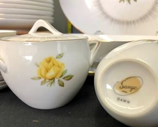 Lot 1124.  Lovely Sanga Dawn China.  96 pc. Includes-- 12 dinner plates, 18 teacups, 12 saucers, 11 bread and butter plates, 11 soup bowls, 12 fruit bowls, 12 salad plates. Serving Items: Large Platter (16"x12"), Divided veggie bowl, small platter, gravy and underplate, veggie bowl, sugar, and creamer. Plate stands and wood stand are not included.   $225.00