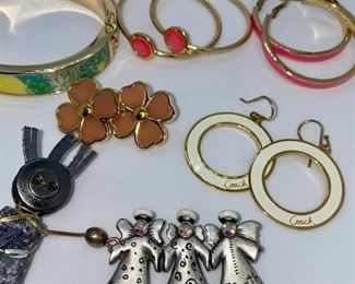 Lot 1338. 	$35.00.  Lot of costume jewelry with some good names like Coach, Kate Spade, Lilly Pulitzer, and a primitive pin.  (10 pc. costume jewelry. folk art pin, orange drop signed earrings, coach key fob w/snowflakes, coach white hoop drop earrings, kate spade pink hoops, lilly pulitzer bangle, 3 angel pin, flower earrings, primitive figurine pin, hoop earrings.	