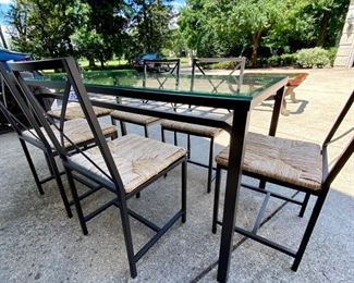 Lot 1392.  $325.00 Glass and metal dining table and 6 metal frame chairs with rush seats ( 2 of the seats need screws to attach seats to frames). 31"x57.5"x30" tall