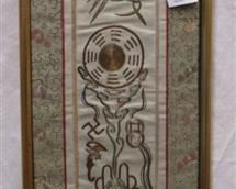 FRAMED CHINESE METALLIC AND SILK THREAD EMBROIDERY. IMAGES INCLUDE A BAT, PHOENIX, SWASTIKA FRUIT AND A URN. FRAME IS 24"x8.5"