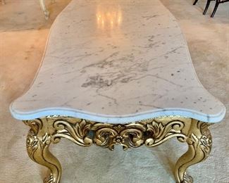 Marble top cocktail table with carved gilt base.  16"H x 24.25"D x 59"W 