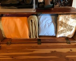 Large cedar chest full of blankets, sheets, rugs.