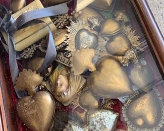 A collection of Ex Votos. Call to inquire about individual pieces. An Ex Voto is a spiritual piece which was a tradition in many houses. They are to be hung in the home and a person's intention is placed inside the hinged open heart. Once the intention is answered the Ex Voto was to be handed over to someone else in the family to do the same thing. They are beautiful pieces in gold and silver with the Immaculate Heart of Mary Insignia on the front and Sacred Heart top. There are several sizes and styles here and they range in price from $95 to $22