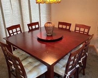 Counter height dining table with 8 chairs and Lazy Susan, Vase, hanging light fixture.