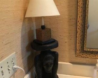 Carved monkey stand, lamp, and nice mirror in bathroom.