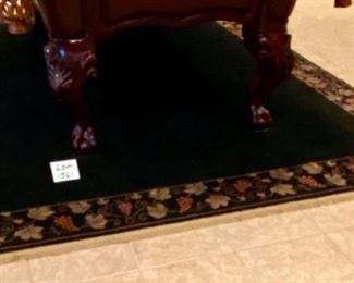 Lot 1561 $325.00. Nice Black Rug with Tan Leaf and Grape Leaf Design around the rim and Tan Fringe 134" L x 91" W (10'10" x 7'7")