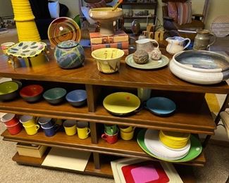 Mid century modern dishes and pottery displayed on high end open sided shelves.