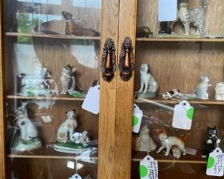 Different kinds of cat and dog figurines in display case.