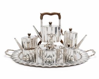 1053
A Mexican Sterling Silver And Wood Tea And Coffee Service
Circa 1940s, Mexico
Each stamped: Sterling / 925 / Hecho en Mexico / DF / RJ
Comprising a wood-handled tipping kettle (15" H x 10.5" W x 6.75" D), a wood-handled coffee pot (9.25" H x 13.25" W x 3.75" D), a wood-handled tea pot (7.75" H x 12.5" W x 4.25" D), a cream jug (5.5" H x 6.75" W x 2.75" D), a sugar pot (5.25" H x 8" W x 3" D), a waste bowl (3.375" H x 4.25" W x 3" D), and a tray (2" H x 31" W x 20" D), 7 pieces
324.445 gross oz. troy approximately
Estimate: $5,000 - $7,000