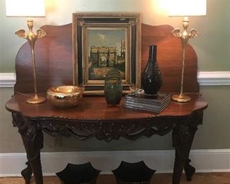 Large round drop leaf carved table!
Brutalist winged form lamps-reproduction.  Paris oil painting.
Carved glass vases.  Black and gold tole planters.