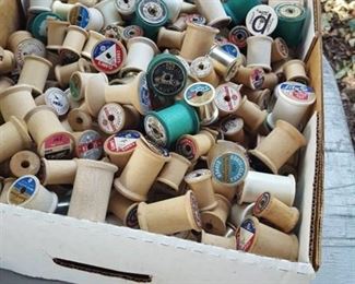 Box of thread spools. Most are wood