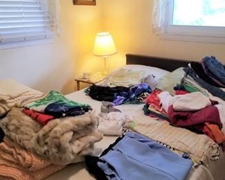 The bed, currently full of clothes