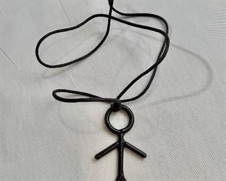 $30 Metal stick figure on leather cord; 29.5"L