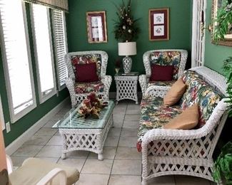 Sun room full of wicker furniture.