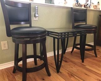 Black cushioned swivel bar stools with wood trim and base.