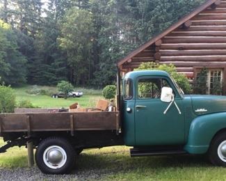 1951 GMC truck in yard of log home