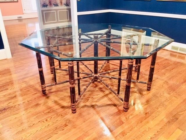 McGuire, Baker--Large octagonal bamboo rattan dining table made in the California organic modern style McGuire for Baker. Features an iron frame 62 inches wide completely wrapped with bamboo poles. The bamboo is lashed together with leather rawhide laces. The table has 9 legs making a beautiful geometric star shaped form. Topped with a pane of 3/4 inch thick beveled glass in an octagonal design. Each leg has a height adjustable foot on the bottom. Excellent joinery and craftsmanship.