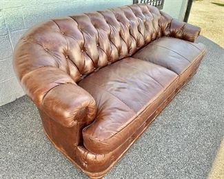 Detail; Side view. Two cushion brown leather tufted back, roll arm couch with bun feet.  Two available. 35.5"H x 41"D x 96"W